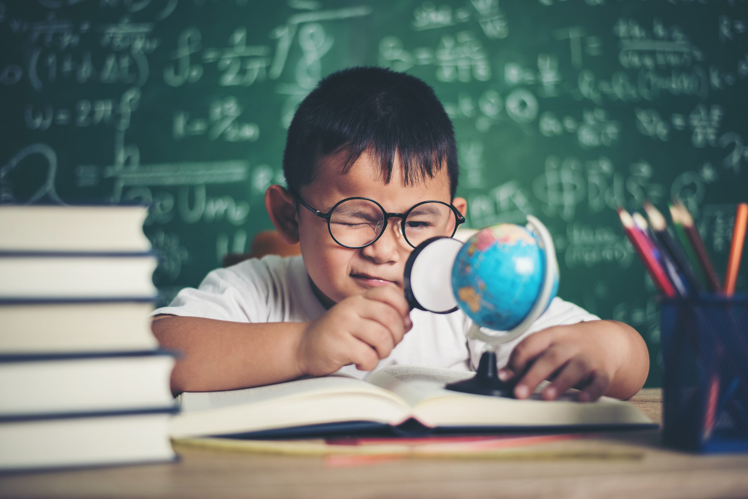 kid observing or studying educational globe model in the classroom.